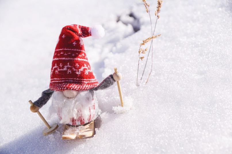 Zwerg mit Mütze auf Ski im Schnee.