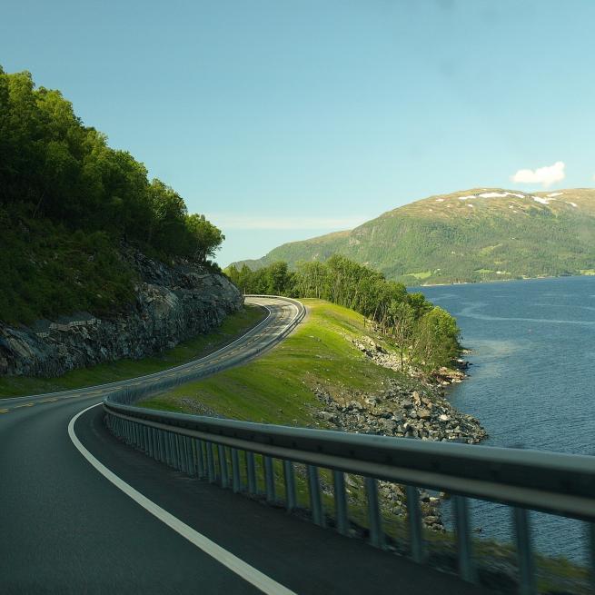 Autofahrt auf der Autobahn mit Aussicht auf einen See und Hügel.